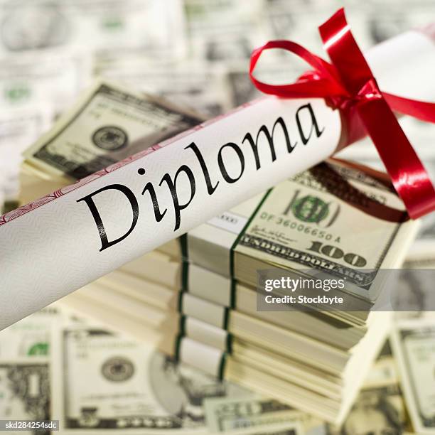 close-up of diploma with ribbon and stacks of one hundred dollar notes - banconota da 20 dollari statunitensi foto e immagini stock