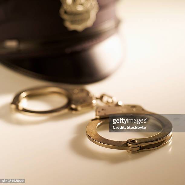 close-up of handcuffs and police hat - hat stock-fotos und bilder