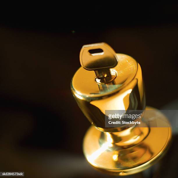 close-up of door knob with key inserted - door stockfoto's en -beelden