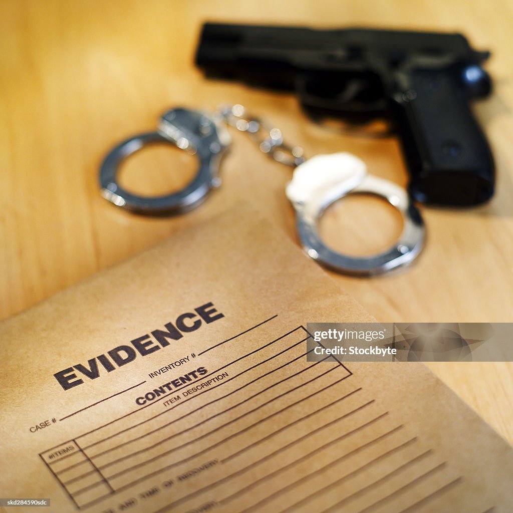 Close-up of gun and handcuffs with evidence bag beside them