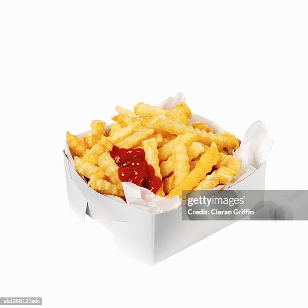 close-up of a carton of french-fries with ketchup - french fries white background stock-fotos und bilder