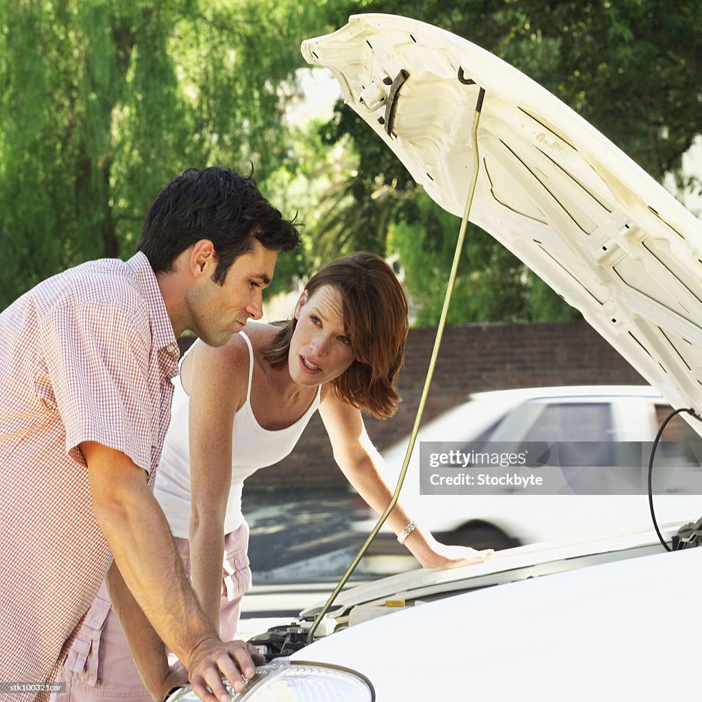 Man and woman leaning over a car engine