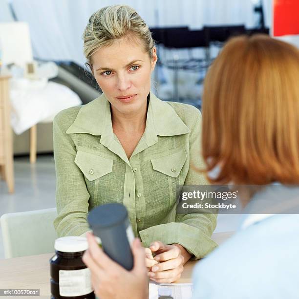 a woman sitting across from a medical professional talking - across stock pictures, royalty-free photos & images