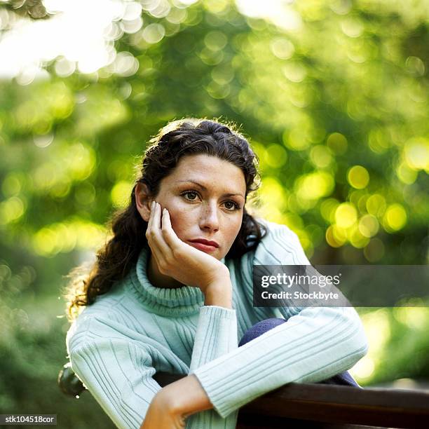 portrait of a young woman resting her chin on her hand - square neckline fotografías e imágenes de stock