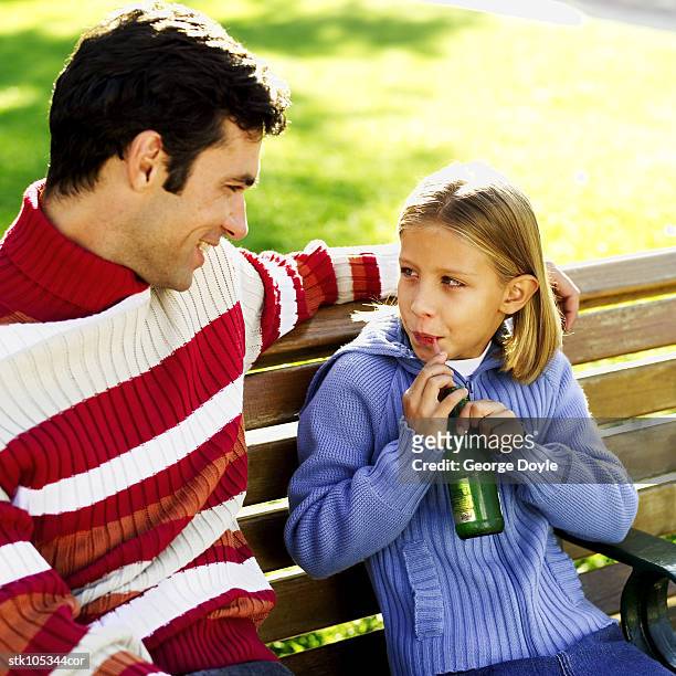 father and daughter sitting at a park bench - square neckline foto e immagini stock