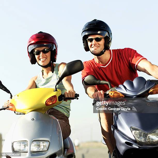 low angle view of a couple on scooters wearing helmets - casco moto blanco fotografías e imágenes de stock