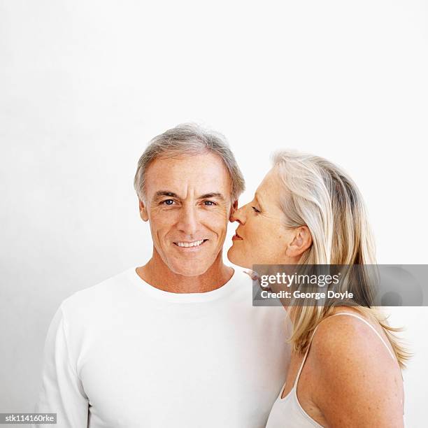 an elderly woman kissing an elderly man on the cheek - studio kiss stock-fotos und bilder
