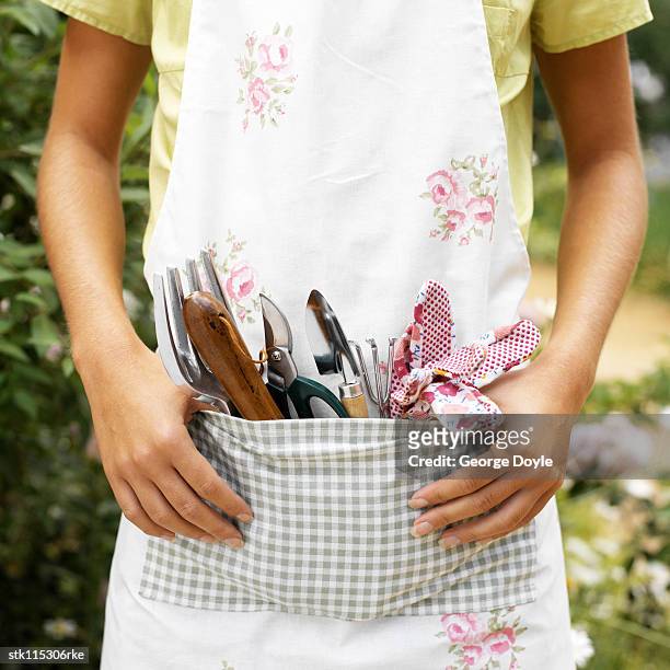 portrait of a young woman wearing an apron with gardening tools in her tool belt - belt stockfoto's en -beelden