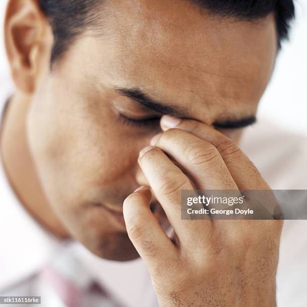 close-up of a young businessman holding the bridge of his nose - holding nose stock pictures, royalty-free photos & images