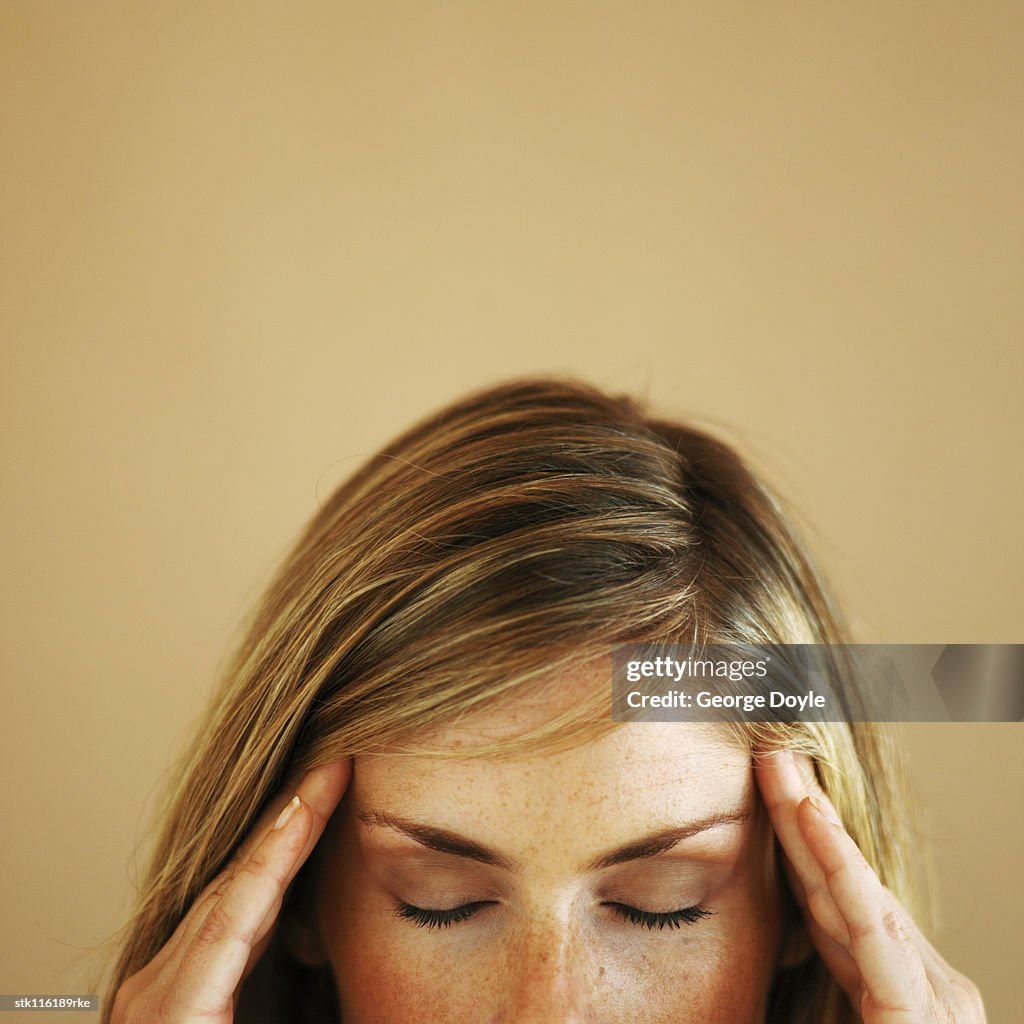 Close-up high section of a young woman touching her head with eyes closed