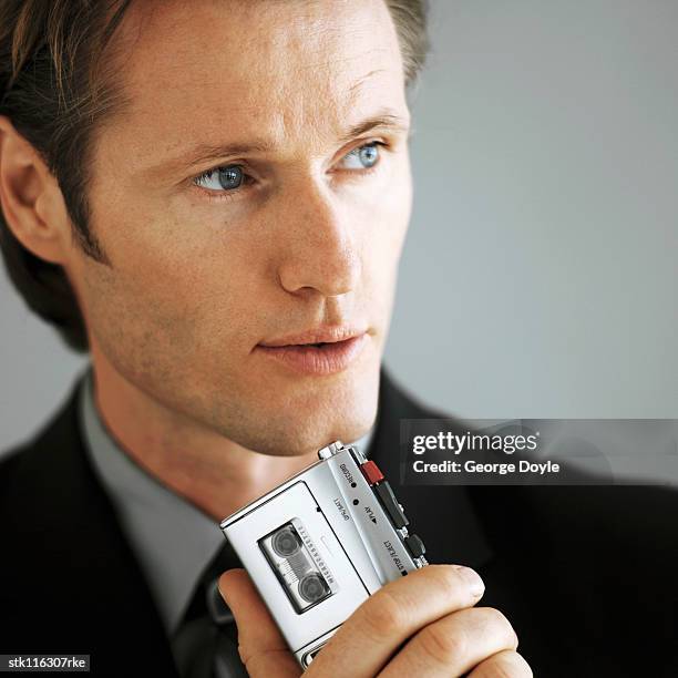 portrait of a young businessman making notes on a cassette recorder - dictaphone stock pictures, royalty-free photos & images