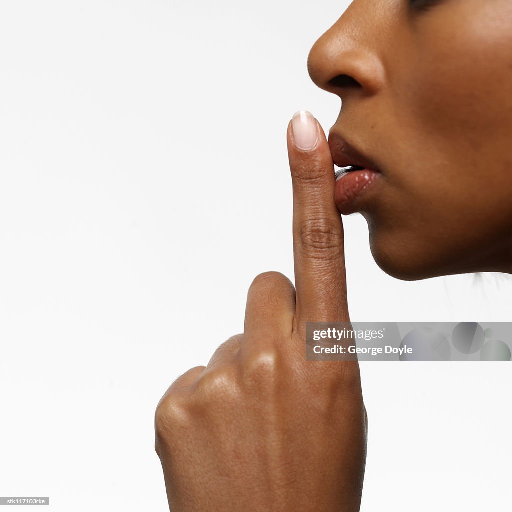 Side profile of a young businesswoman with her finger on her lips