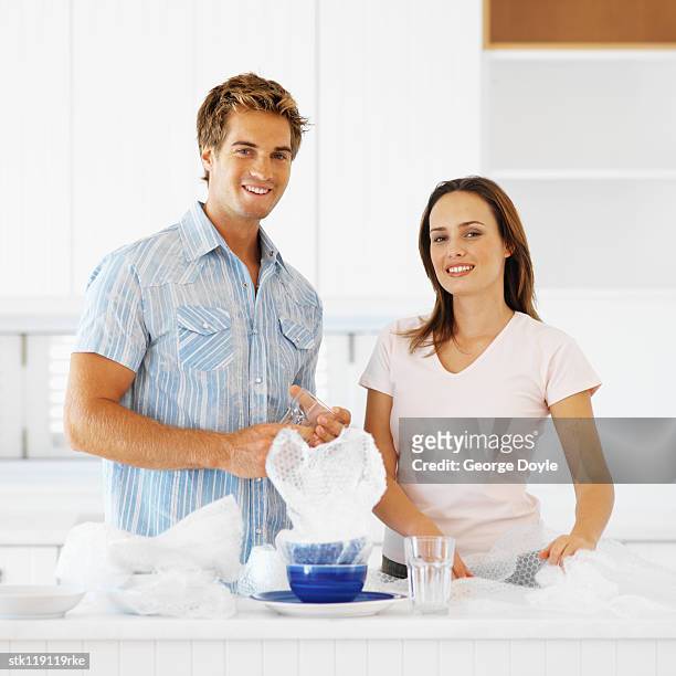 portrait of a young couple unpacking crockery in a kitchen - square neckline fotografías e imágenes de stock