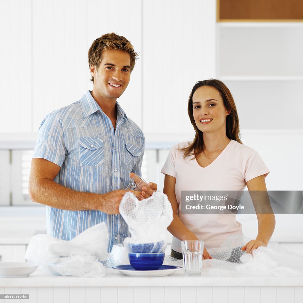 Portrait of a young couple unpacking crockery in a kitchen