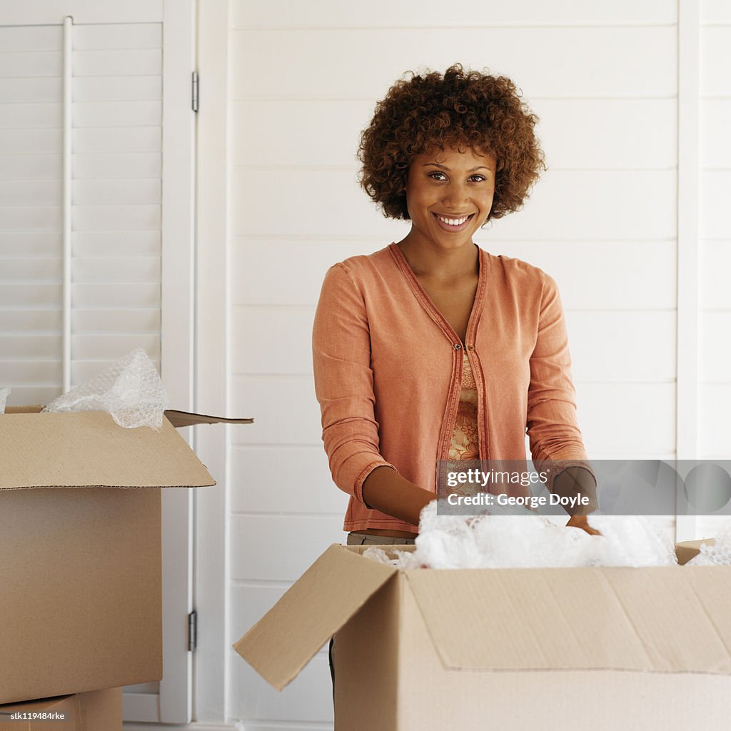 Portrait of a young woman unpacking a cardboard box