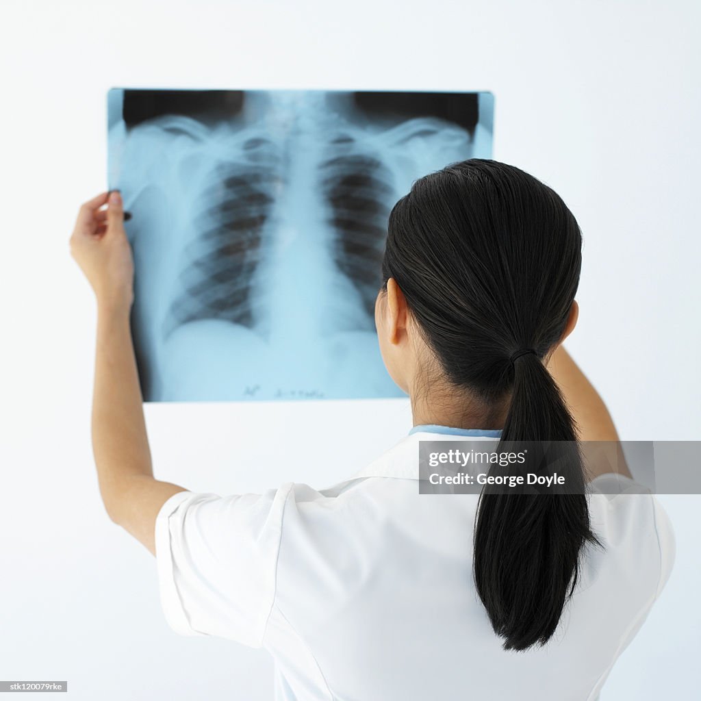 Rear view of a female medical professional looking at an x-ray