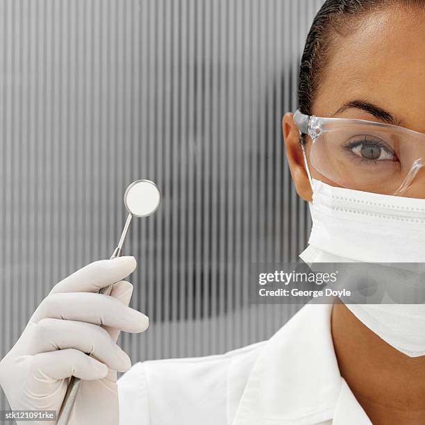 portrait of a young female dentist holding a dental instrument - dentist phobia stock-fotos und bilder
