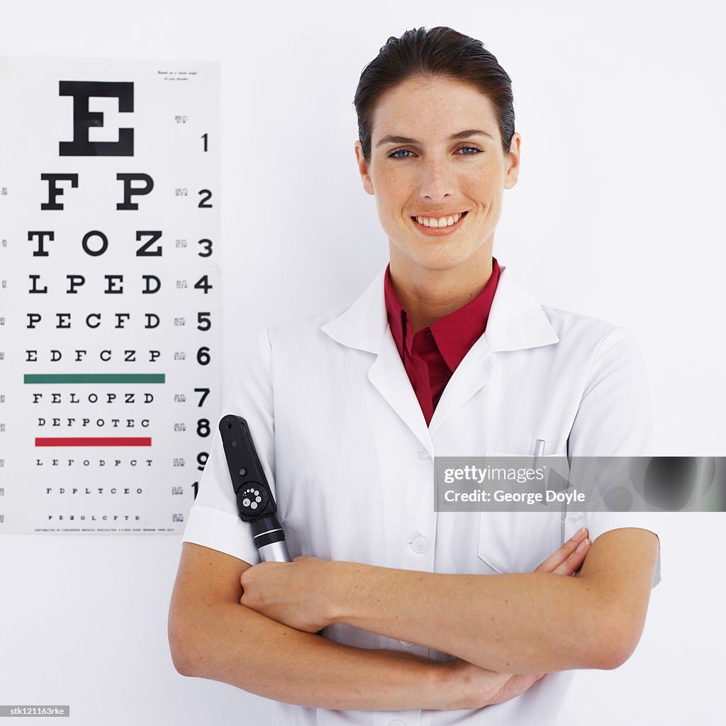 Portrait of a young female optician standing next to a eye chart