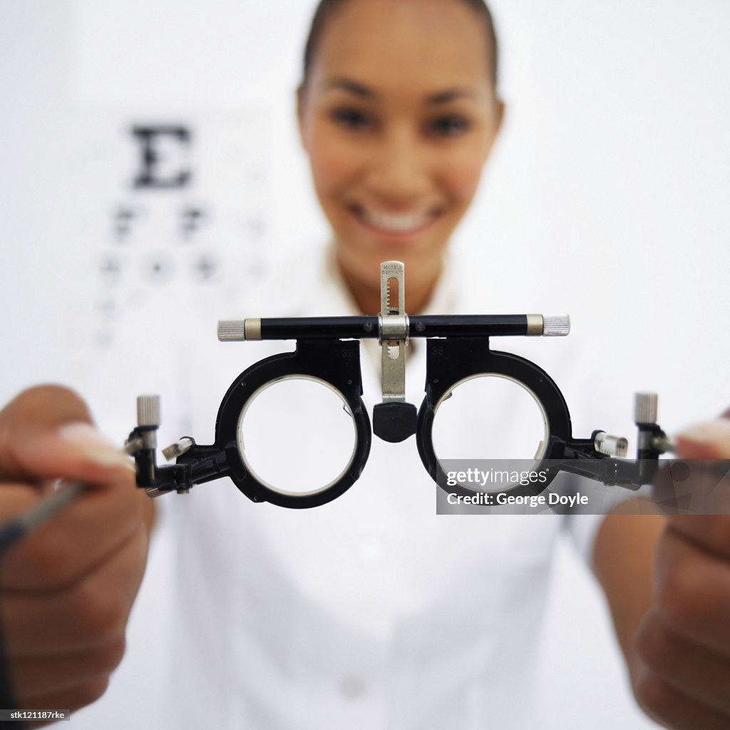 Close-up of eye testing spectacles in a young female optometrists hands (blurred)