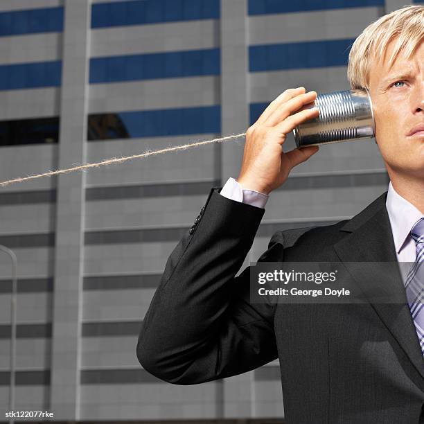 businessman outdoors with can and string to his ear listening - string - fotografias e filmes do acervo