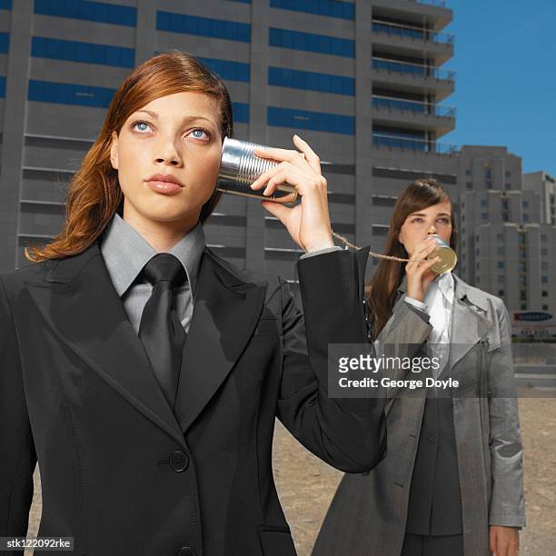 two young businesswomen talking listening with tin cans and string - string - fotografias e filmes do acervo