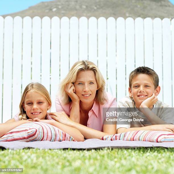 daughter and son lying next to mother on the lawn - happy tween girls lying on grass stock pictures, royalty-free photos & images