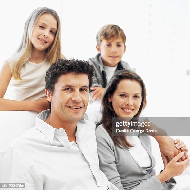 portrait of a young couple with their son and daughter (8-12) - front view portrait of four children sitting on rock stock-fotos und bilder