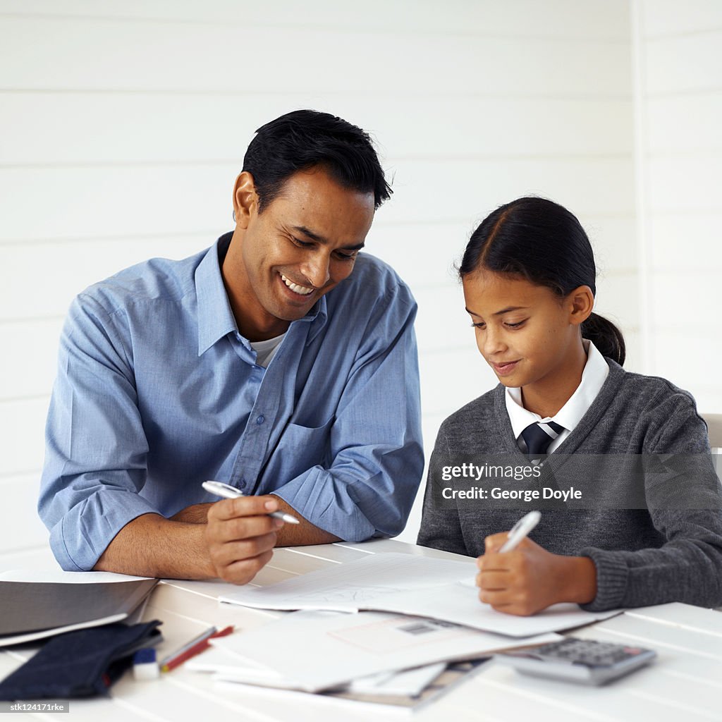 Young man helping his teenage daughter with homework (11-13)