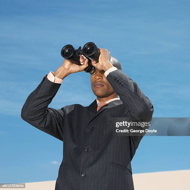 businessman in desert looking through binoculars - spy glass businessman stock pictures, royalty-free photos & images