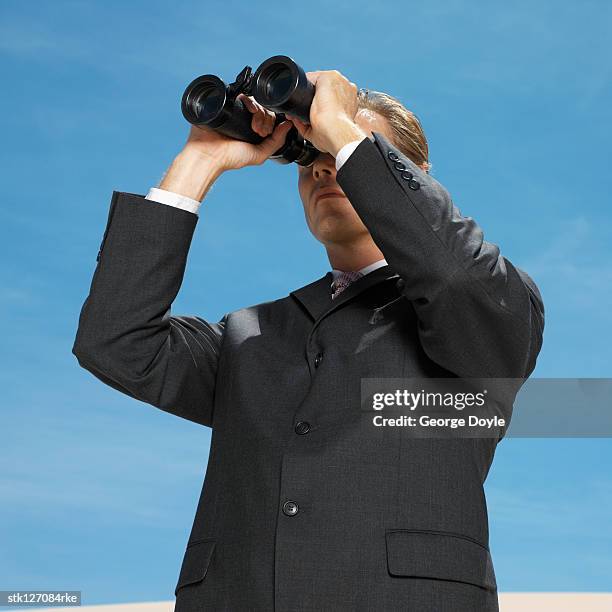 businessman in desert looking through binoculars, low angle view - informational stock pictures, royalty-free photos & images