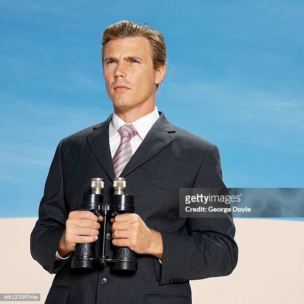 businessman in desert holding binoculars, low angle view - busboys and poets peace ball voices of hope and resistance stockfoto's en -beelden