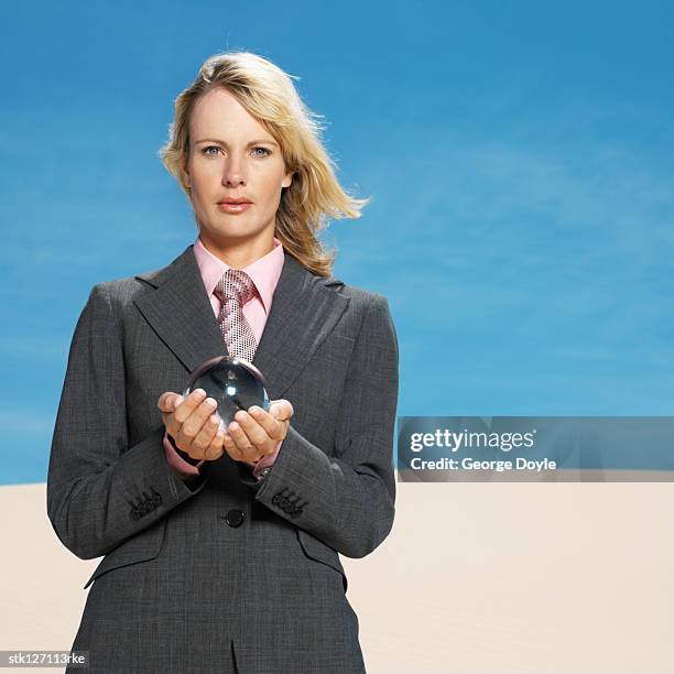 businesswoman in desert holding crystal ball, low angle view, portrait - crystal - fotografias e filmes do acervo