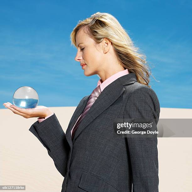 side profile of a young woman holding a crystal ball in the desert - crystal stock-fotos und bilder