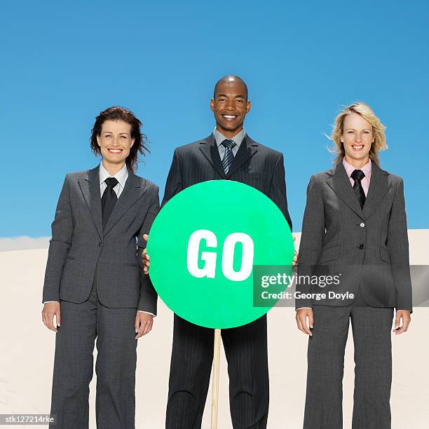 portrait of young business executives standing holding a green go signboard - busboys and poets peace ball voices of hope and resistance stockfoto's en -beelden