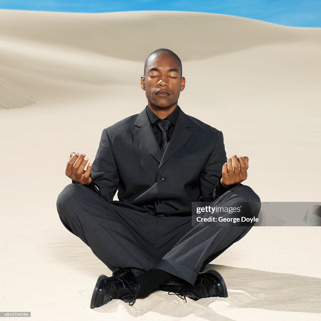 Businessman doing yoga in the desert