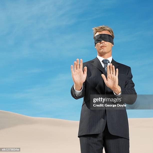 young man standing and his eyes covered with a blindfold - restraining device stock pictures, royalty-free photos & images