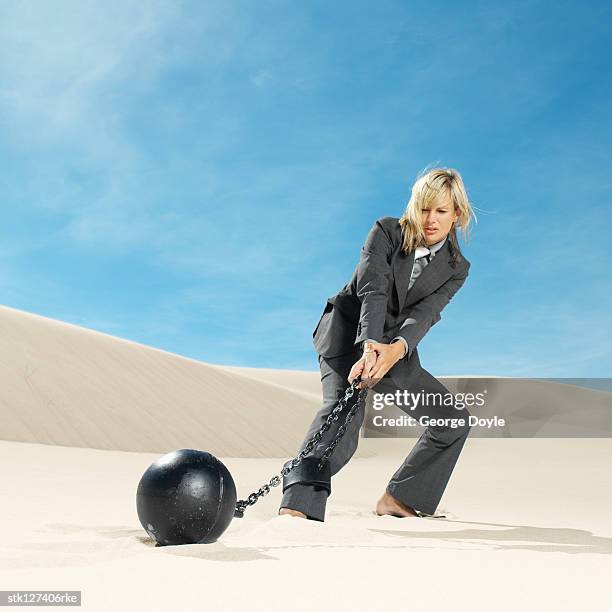 businesswoman wearing ball and chain in desert, low angle view - restraining device stock pictures, royalty-free photos & images