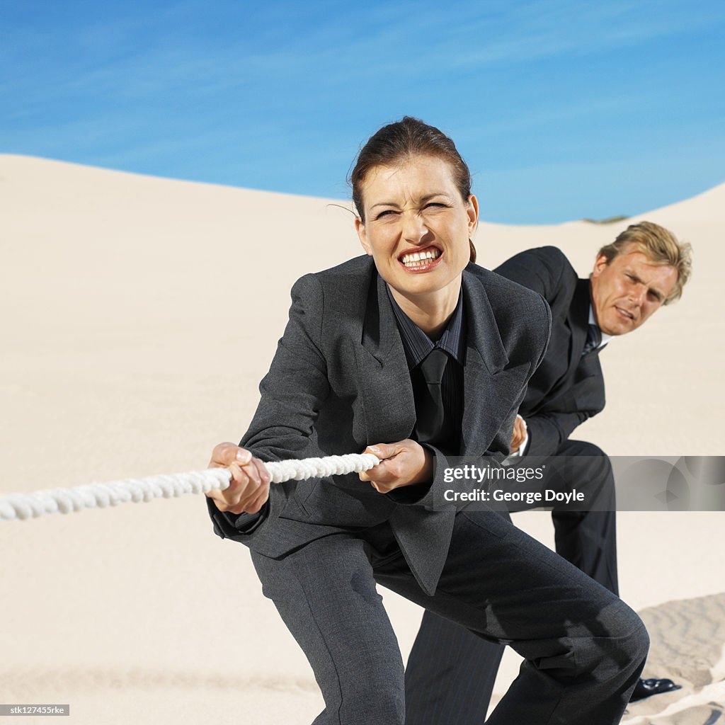 Businesspeople playing tug of war in desert