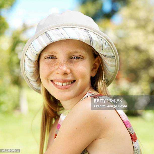 portrait of a girl (10-12) sitting outdoors wearing a hat - hat stock-fotos und bilder