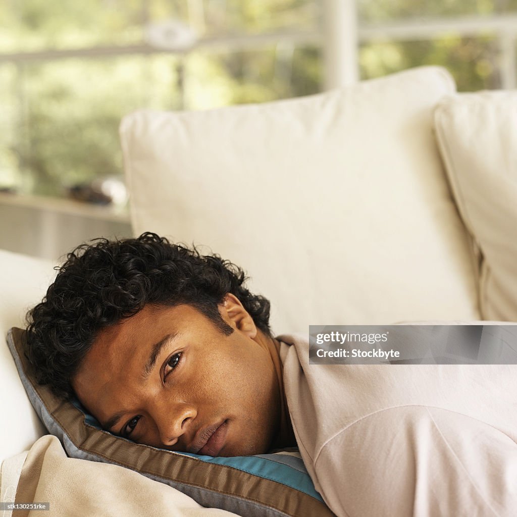 Close-up of a young man lying on his stomach on a couch