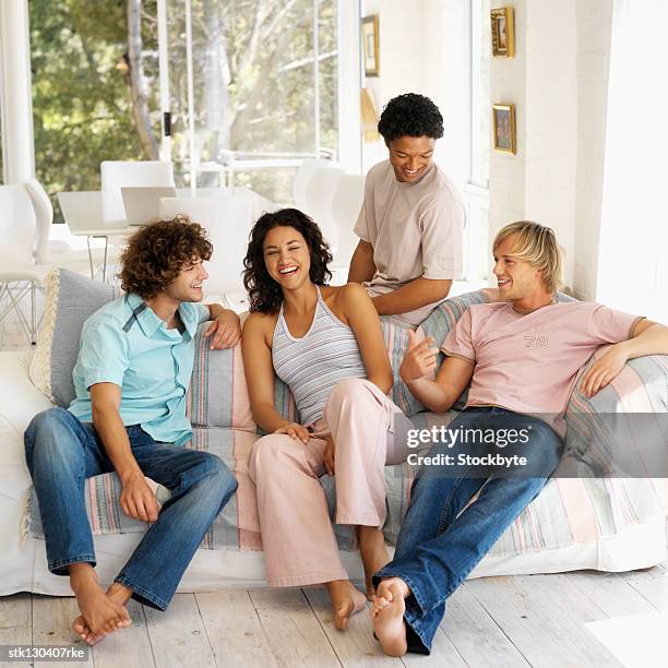 portrait of a young woman sitting in a living room with three young men - living stock-fotos und bilder