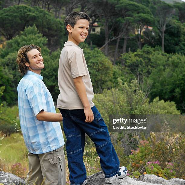 rear view of a boy standing on a rock with his father in the wilderness - brian may signs copies of we will rock you at virigin megastore september 28 2004 stockfoto's en -beelden