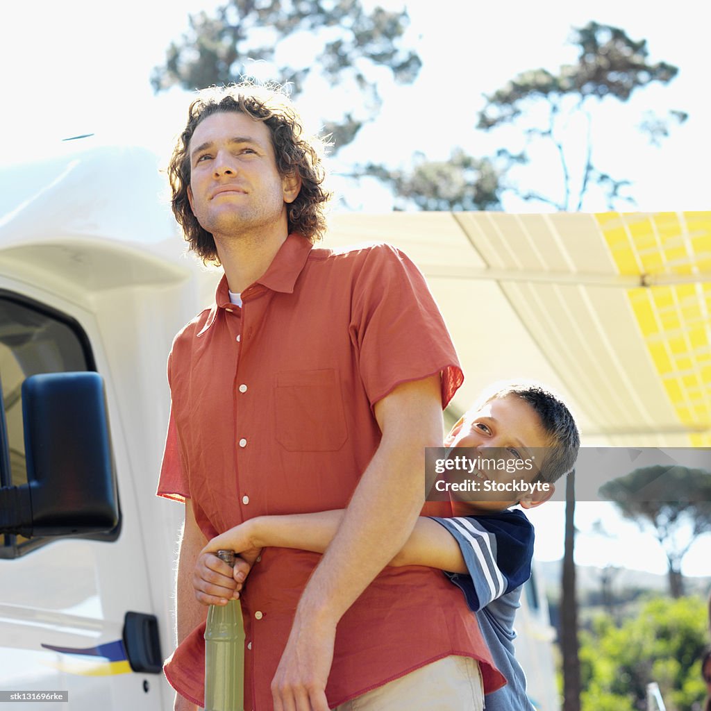 Close up of father and son (8-9) hugging holding a bottle of soda