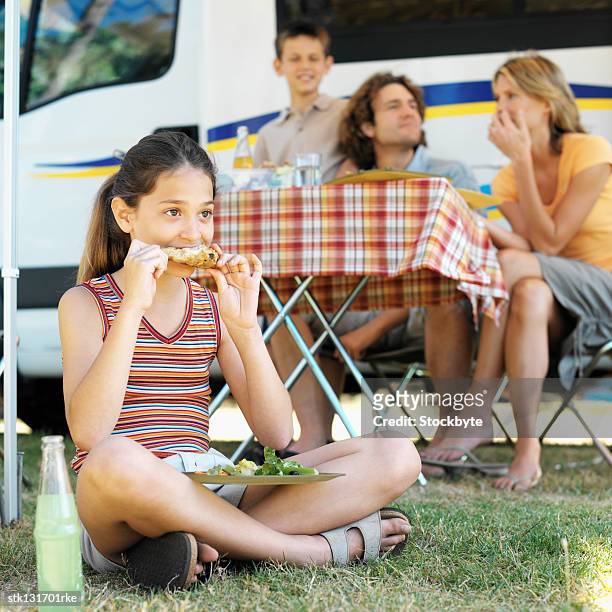 close up of father mother son (8-9) sitting beside table and daughter (10-11) sitting on grass eating - gen z studio brats premiere of chicken girls arrivals stockfoto's en -beelden