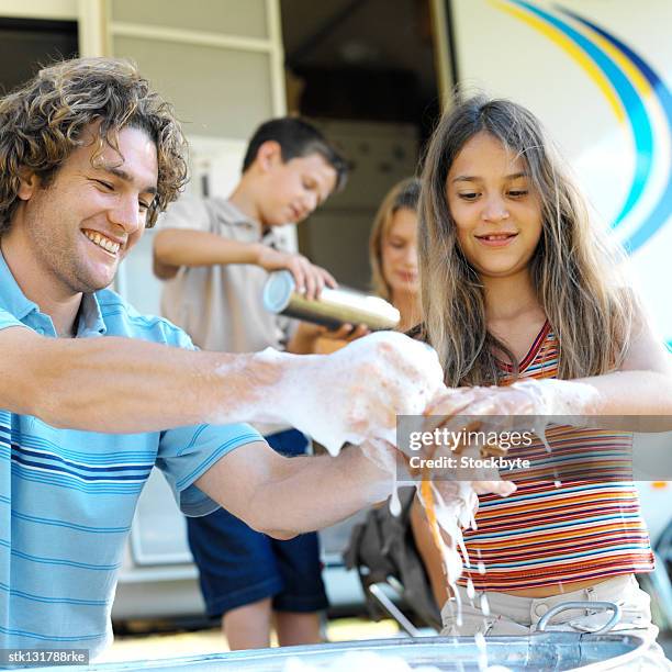 close-up of a man washing his daughters hands in a metal tub - washing tub stockfoto's en -beelden