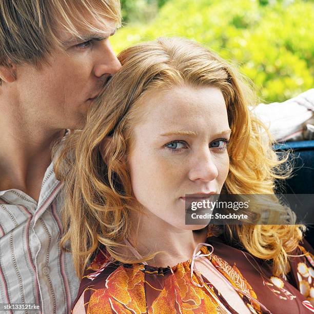 close-up of a woman lying in a mans lap on a patio swing - donna capelli rossi foto e immagini stock