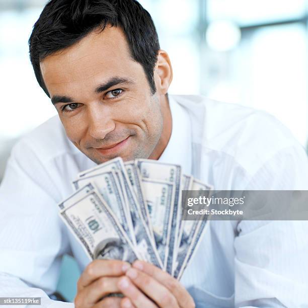 front view portrait of businessman holding a stack of american dollar notes - kärleken till pengar bildbanksfoton och bilder