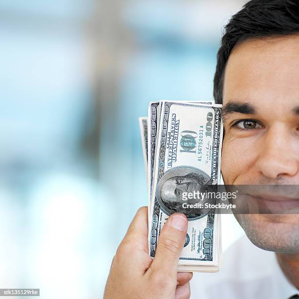 close-up of a man holding hundred dollar bills against his cheek - kärleken till pengar bildbanksfoton och bilder