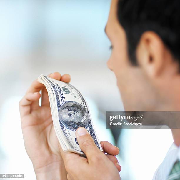 close-up of a man holding a wad of hundred dollar bills - young urban professional person stock-fotos und bilder