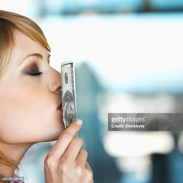 side view of businesswoman kissing a hundred dollar bill - kärleken till pengar bildbanksfoton och bilder